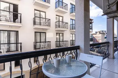a balcony with a table and chairs and a building at Gitane 1-Bedroom Apartment in Larnaca in Larnaka