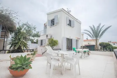 a white house with white chairs and a table at Peaceful Cozy Home Great Location in Protaras