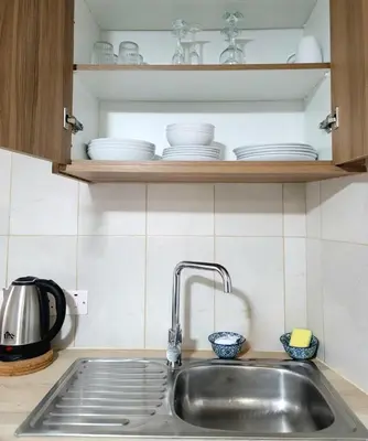 a kitchen sink with plates and bowls on a shelf at Palm Sea Suite 17 in Larnaka