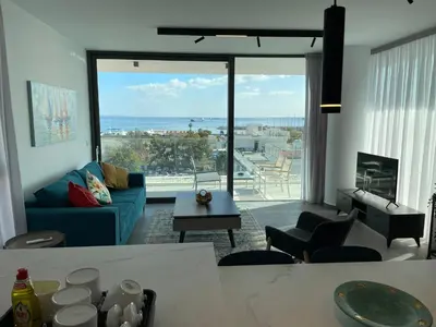 a living room with a blue couch and a large window at Gaia Seaview Apartment 1 in Larnaka