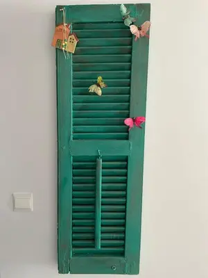 a green shutter with two birds on top of it at Gaia Seaview Apartment 1 in Larnaka