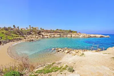 a beach with blue water and a rocky island at Villa Queen Alexandra in Protaras