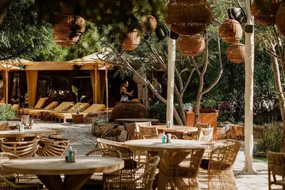 a patio with tables and chairs and a woman in the background at Villa Queen Alexandra in Protaras