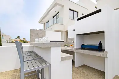 a white house with a bench and a blue pool at Villa Queen Alexandra in Protaras
