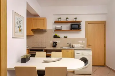 a kitchen with a white table and a washing machine at Palm Beach Apartment by TrulyCyprus in Limassol
