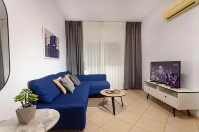 a living room with a blue couch and a tv at Palm Beach Apartment by TrulyCyprus in Limassol