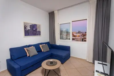 a blue couch in a living room with a tv at Palm Beach Apartment by TrulyCyprus in Limassol