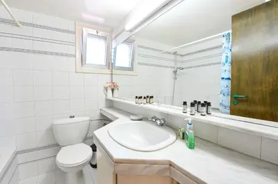 a white bathroom with a toilet and a sink at Villa 361-Walk to Protaras Fig Tree Bay & Amenities in Protaras