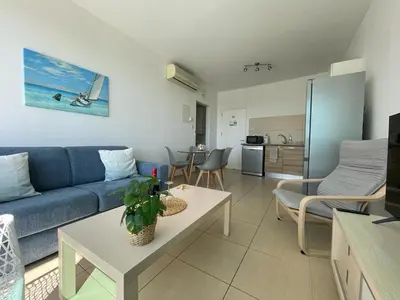 a living room with a blue couch and a kitchen at MagesticView seafront apartment in Protaras