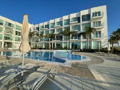 a hotel with an umbrella and chairs and a swimming pool at MagesticView seafront apartment in Protaras
