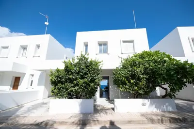 a white building with trees in front of it at Jasmine Sea Front Villa in Protaras