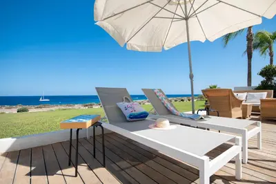 a white bench with an umbrella on a deck at Jasmine Sea Front Villa in Protaras