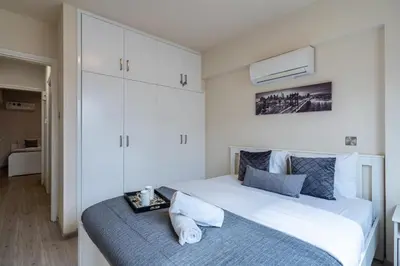 a bedroom with a large white bed with a blue blanket at Vox 2-Bedroom Apartment in Larnaca in Larnaka