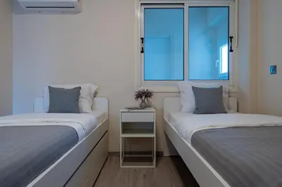 two beds in a room with two windows at Vox 2-Bedroom Apartment in Larnaca in Larnaka