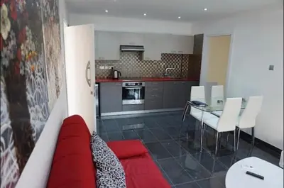 a living room with a red couch and a kitchen at Ayia Napa Luxury Apartment in Ayia Napa