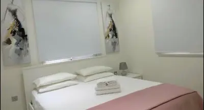 a bedroom with a bed with white sheets and a window at Ayia Napa Luxury Apartment in Ayia Napa