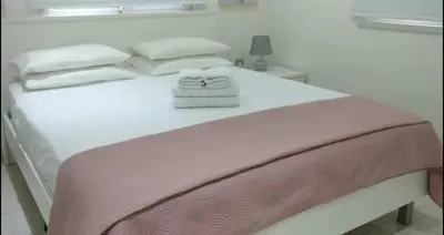 a white bed with a pink blanket and white pillows at Ayia Napa Luxury Apartment in Ayia Napa