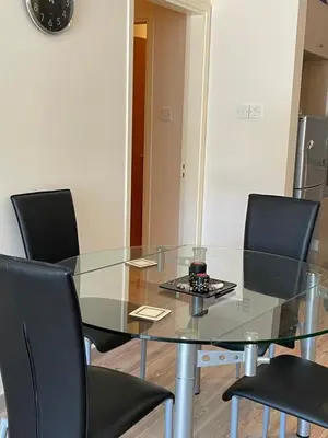 a glass dining room table with chairs and a clock at Belleview Heights in Limassol