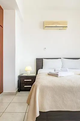 a bedroom with a large bed and a night stand at Villa Sunnyside Mandali by Ezoria Villas in Protaras