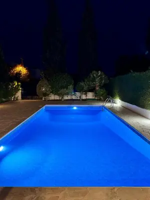 a blue swimming pool at night at Villa Lorena Protaras in Protaras