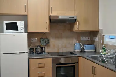 a kitchen with wooden cabinets and a white refrigerator at Sweet Retreat in Paralimni