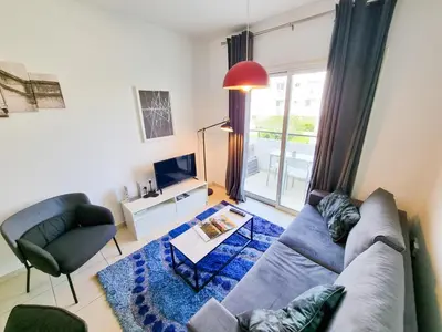 a living room with a couch and a tv at Seaside Heaven Apartment With Pool in Larnaka