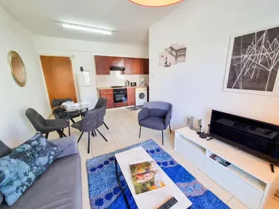a living room with a couch and a tv and a table at Seaside Heaven Apartment With Pool in Larnaka