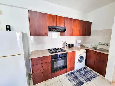 a kitchen with wooden cabinets and a stove top oven at Seaside Heaven Apartment With Pool in Larnaka