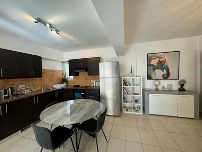 a kitchen with a table and a stainless steel refrigerator at Seaview Harmony in Larnaka