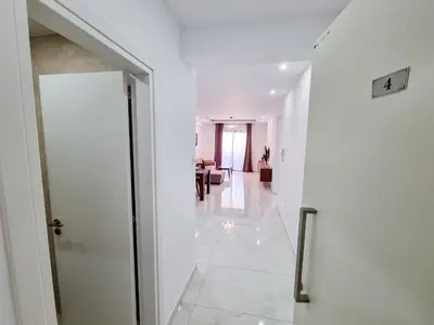 a white hallway with a door and a living room at Sea Bay Apartment in Larnaka