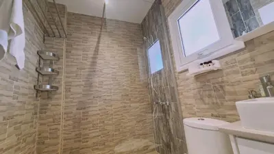 a bathroom with a shower and a toilet and a window at STAY Lavish Studio in Ayia Napa