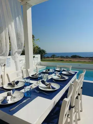 a long table with blue and white plates and chairs at Narcissus 19 in Paralimni