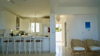 a kitchen with white cabinets and bar stools at Narcissus 18 in Paralimni