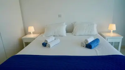 a white bed with blue and white pillows on it at Narcissus 18 in Paralimni