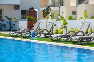 a row of chaise lounge chairs next to a swimming pool at Mythical Sands AM10 in Paralimni