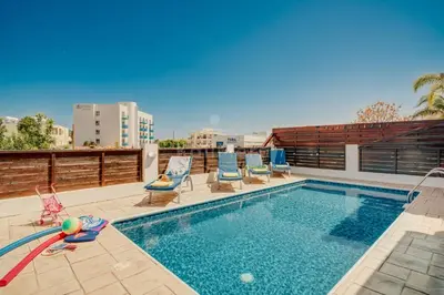 a swimming pool with chaise lounge chairs next to a building at Villa Sunrise Pernera in Paralimni