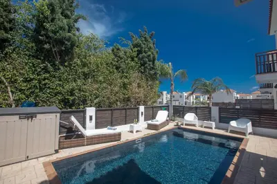 a swimming pool with two chairs and a swimming pool at Sunny Side Up Villa in Protaras