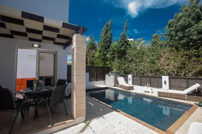 a patio with a pool and a table and chairs at Sunny Side Up Villa in Protaras
