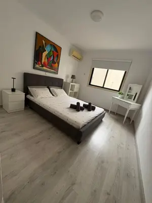 a bedroom with a large bed and a wooden floor at Theodoros Apt.79 in Paralimni