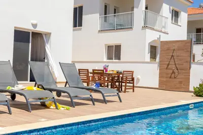 a pool with chairs and a table next to a building at Napa Bay View Villa 3 in Ayia Napa