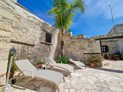 a group of chairs and a palm tree on a patio at Aphrodite's Pool Retreat in Skarinou