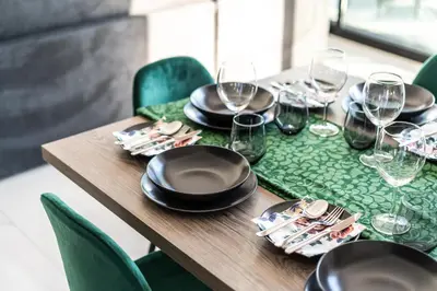 a wooden table with black plates and wine glasses at Tsiolakki Homes Luxury Villas in Protaras