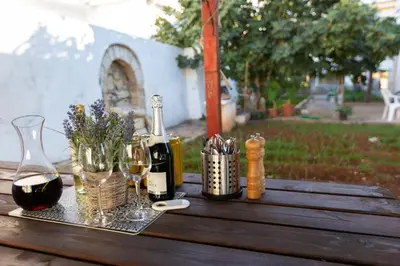 a wooden table with wine bottles and glasses on it at Aladdin's Hostel in Larnaka