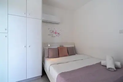 a white bedroom with a bed and a white cabinet at Andrea 3-Bedroom Apt in Mackenzie in Larnaka