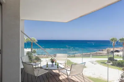 a balcony with a table and chairs and a view of the ocean at Thalassa Luxury Apartment in Protaras